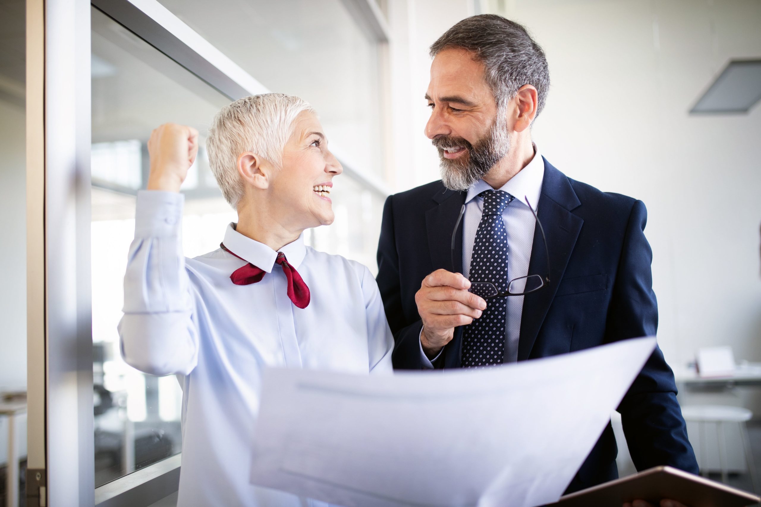 Berufsunfähigkeitsversicherung im Alter: Senior-Geschäftsleute feiern einen Business-Erfolg.