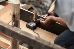 Berufsunfähigkeit Berufe: Zimmermann arbeitet mit Hammer und Meter am Bau.